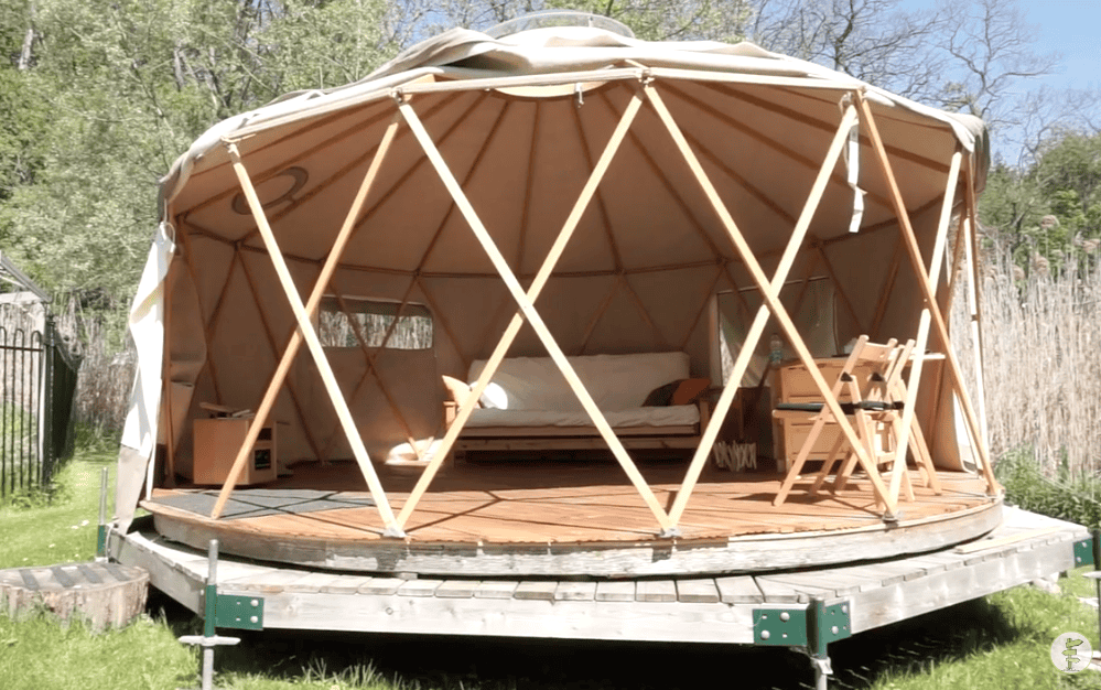 Yurta outdoor glamping tent with wooden deck and cozy interior.