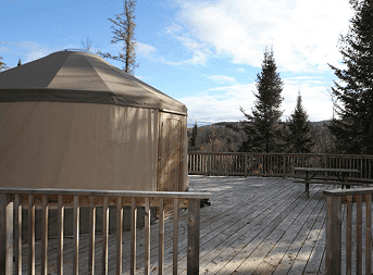 Yurt on wooden deck surrounded by nature, perfect for outdoor relaxation and unique accommodations.