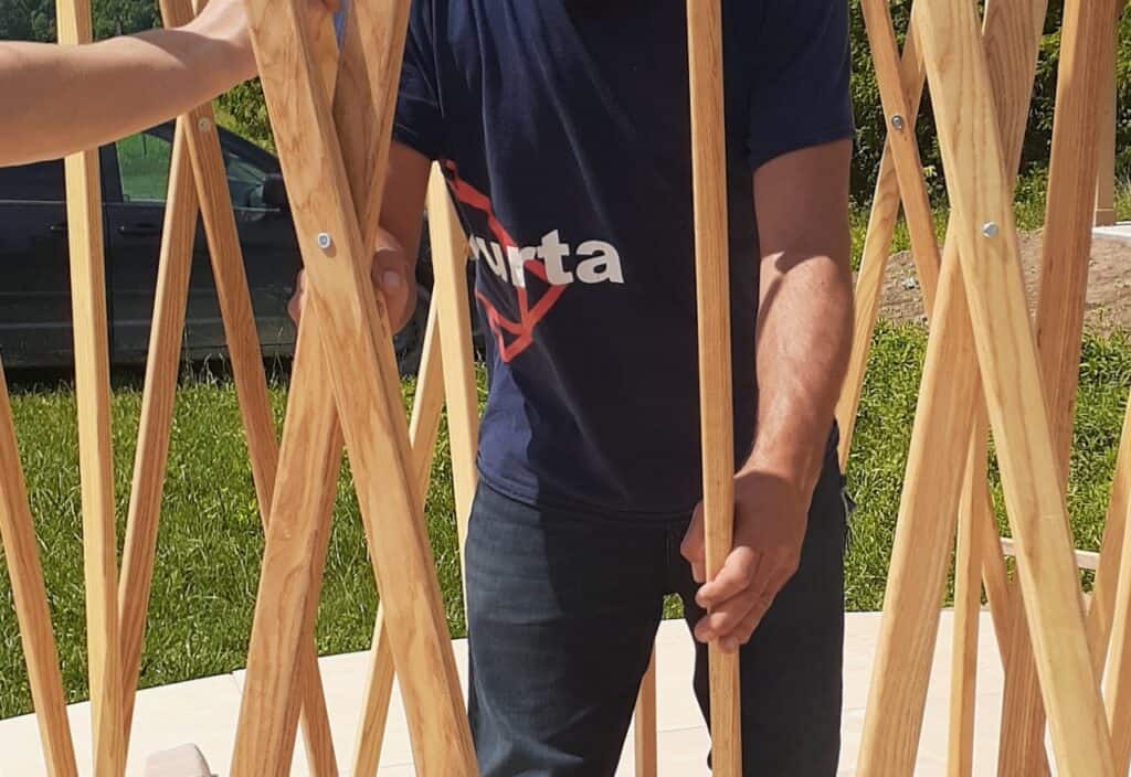 Wooden frame structure of a yurta under construction outdoors.