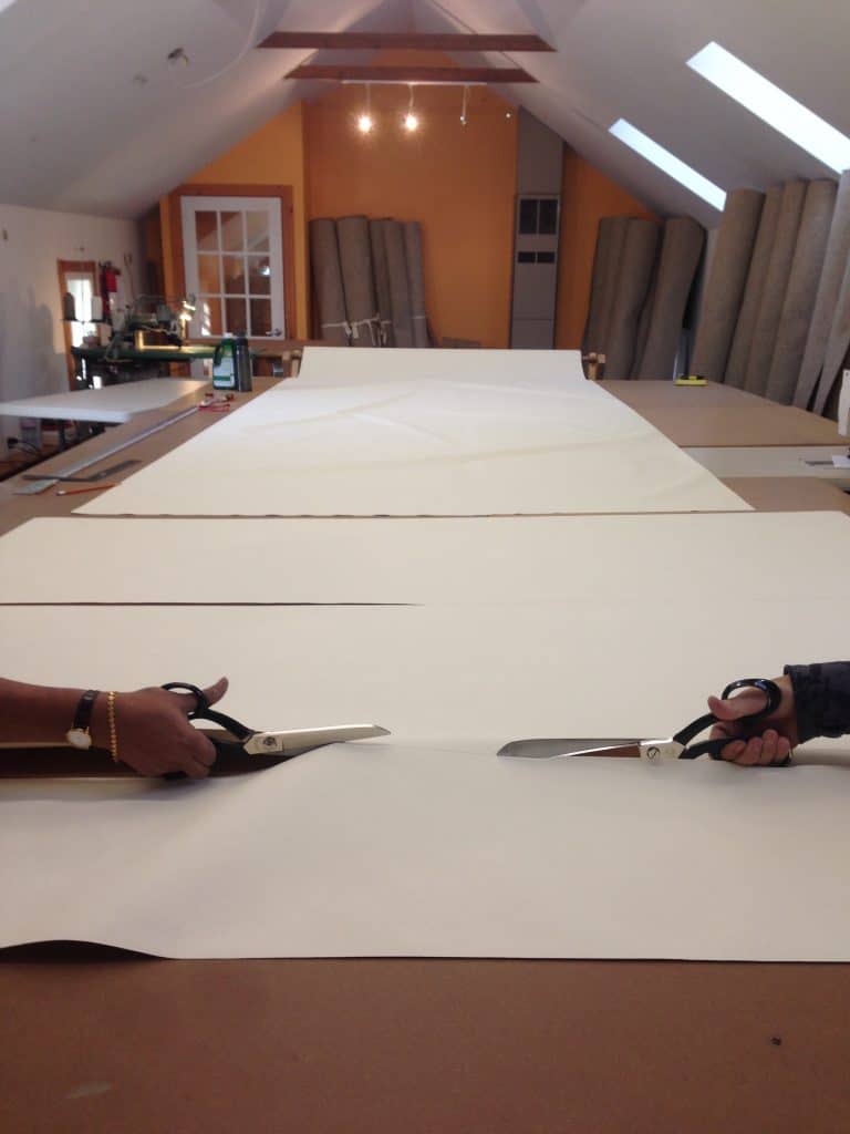 Two hands cutting yurt fabric in shop