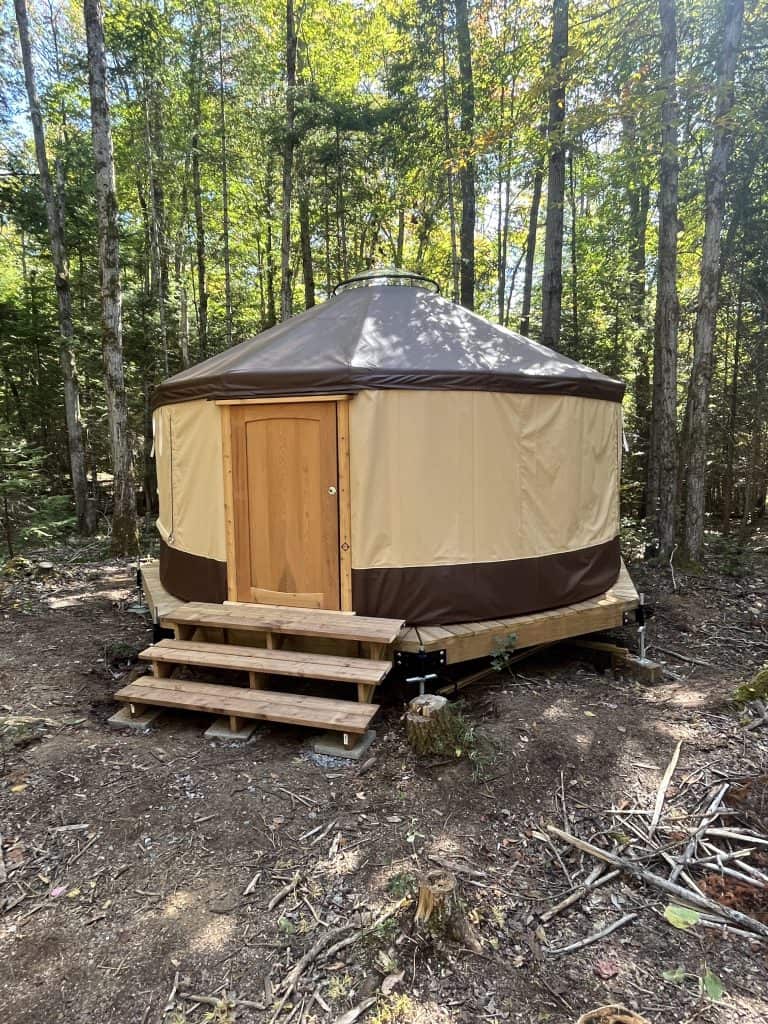 Brown yurt with tan stripe on wall in forest